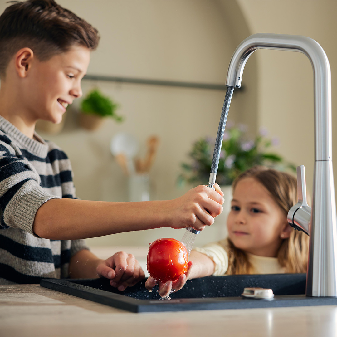 Les enfants lavent les légumes dans la cuisine.