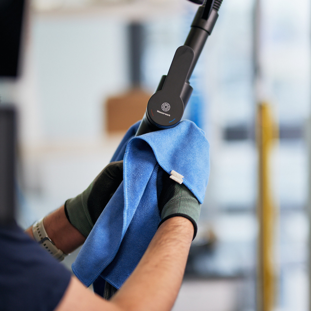 Werknemer maakt keukenkraan schoon met handdoek