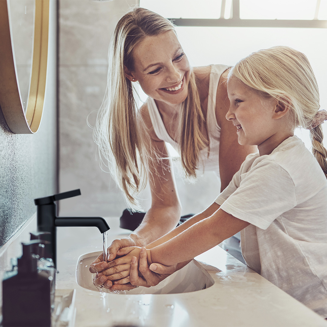 Mother and daughter washing hands in bathroom